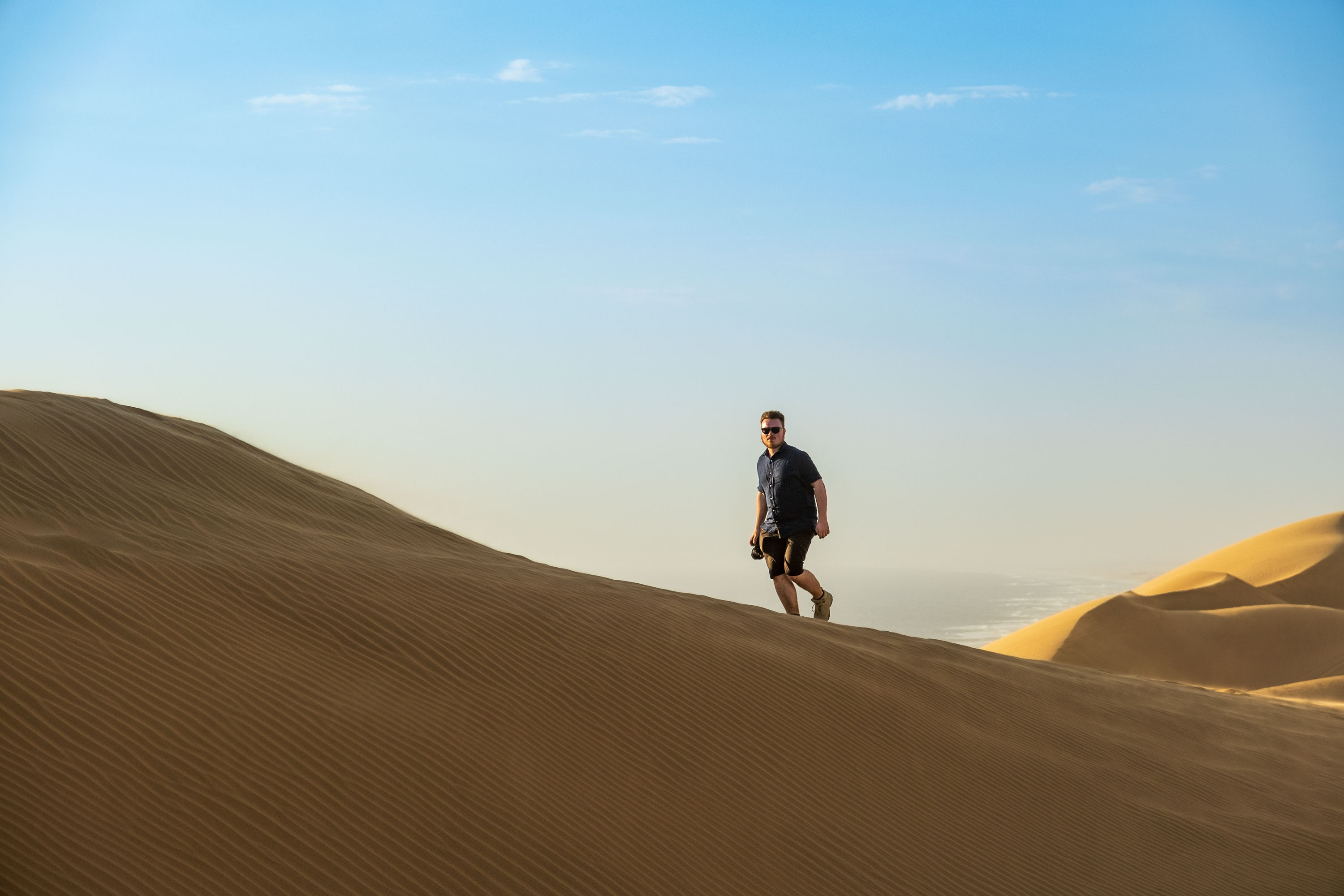Felix Lukas Kübler läuft als Reisefotograf über eine Dünenkante.