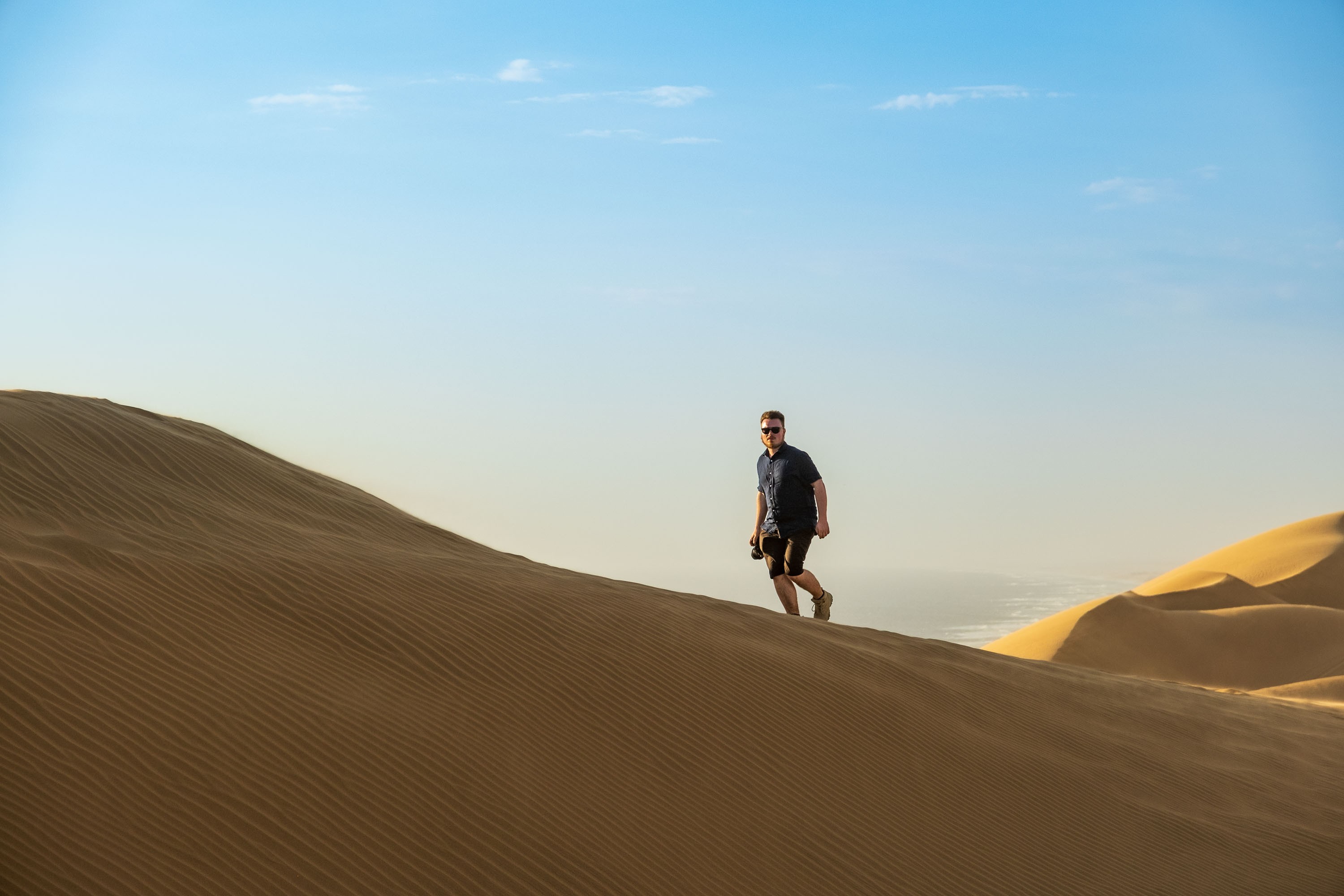 Reisefotograf Felix Lukas Kübler läuft eine Düne bei Sandwich Harbour, Namibia, beim Sonnenuntergang.